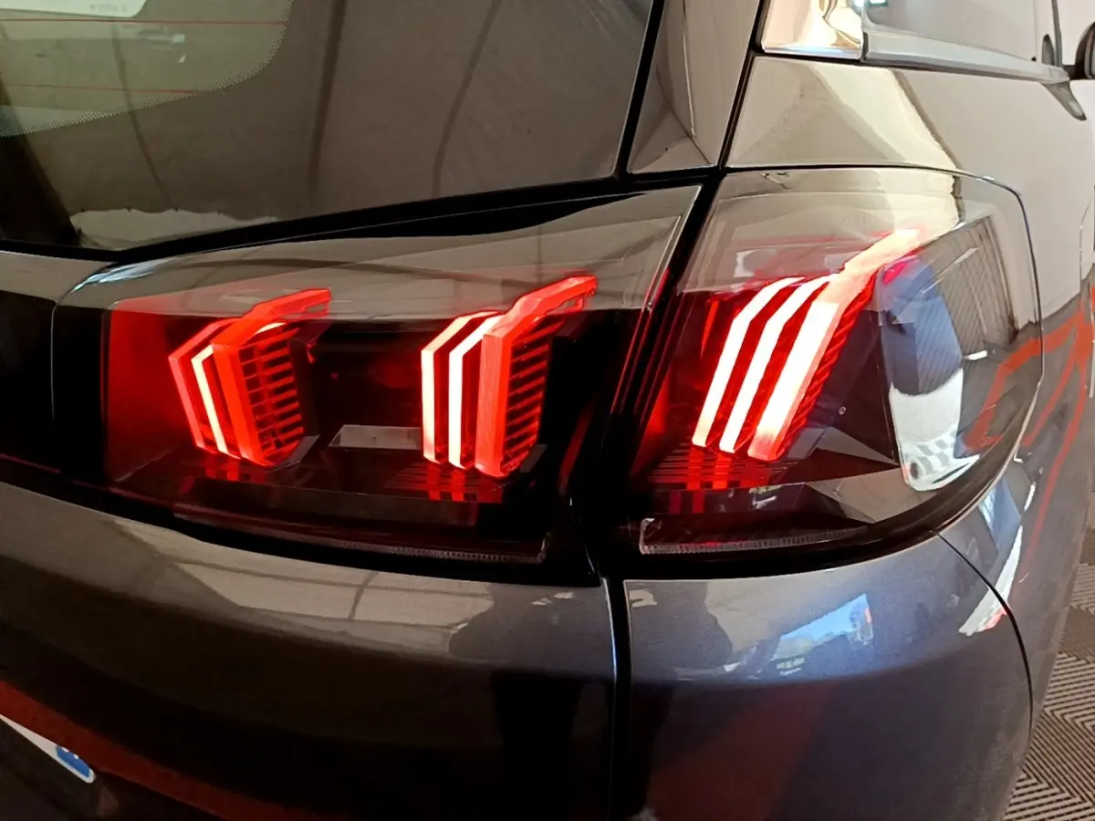 Gros plan sur les feux arrière LED rouges du côté droit d’un Peugeot 5008 gris clair de 2021.