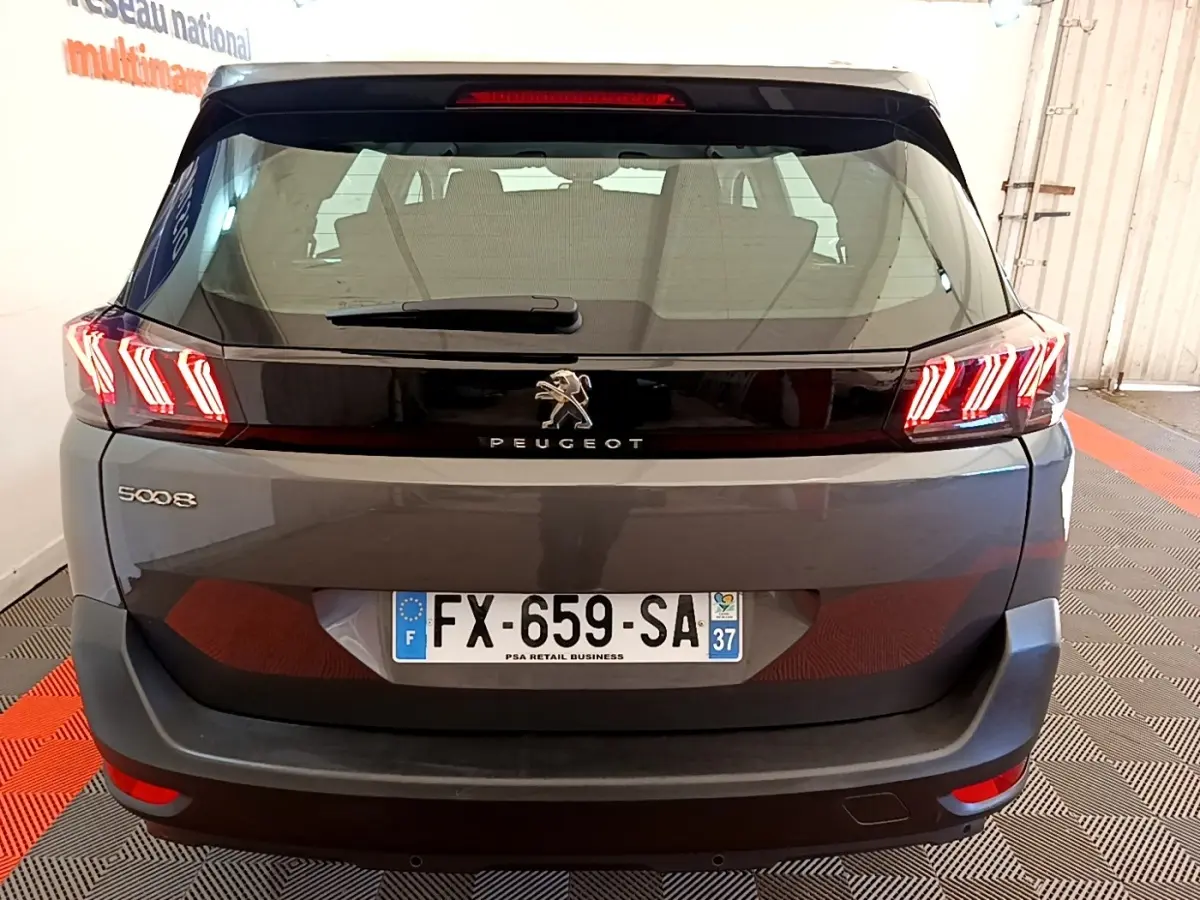 Vue arrière d’un Peugeot 5008 gris clair avec feux LED distinctifs en forme de griffes et plaque d’immatriculation française.