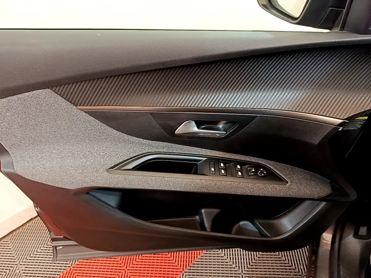 Vue intérieure du panneau de porte avant gauche du Peugeot 5008 gris clair, avec commandes électriques et poignée argentée.