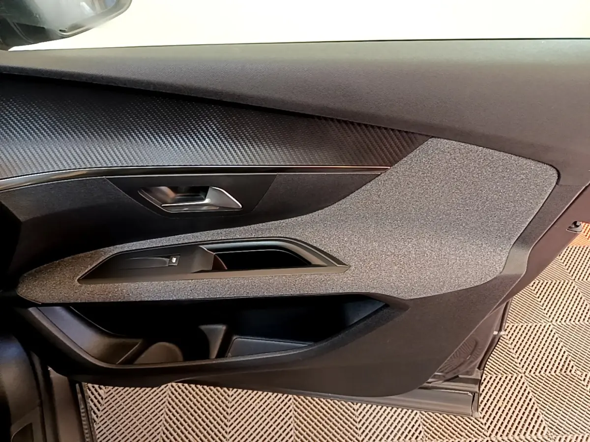 Vue rapprochée de la porte côté conducteur du Peugeot 5008 gris clair, mettant en valeur les matériaux texturés et la poignée intégrée.