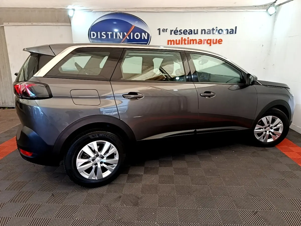 Vue de profil côté droit d’un Peugeot 5008 gris clair garé en intérieur avec jantes alliage et feux arrière LED.