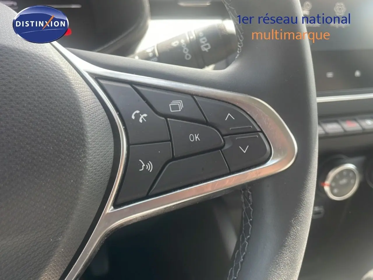 Gros plan sur les commandes multifonctions à droite du volant d’une Renault Clio blanche, intérieur noir avec coutures visibles.