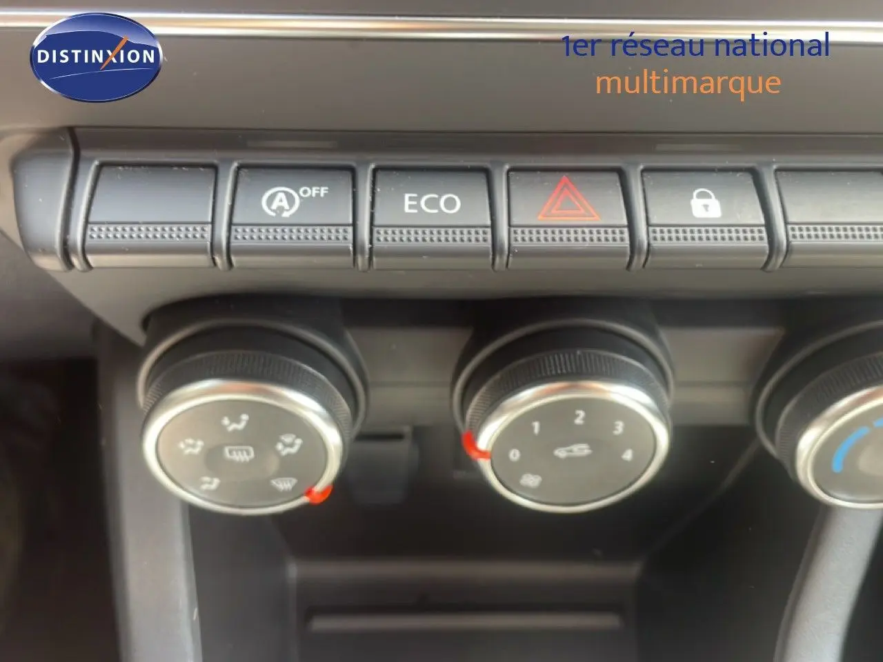 Gros plan sur les commandes de climatisation et boutons de fonction d’une Renault Clio blanche, intérieur noir.