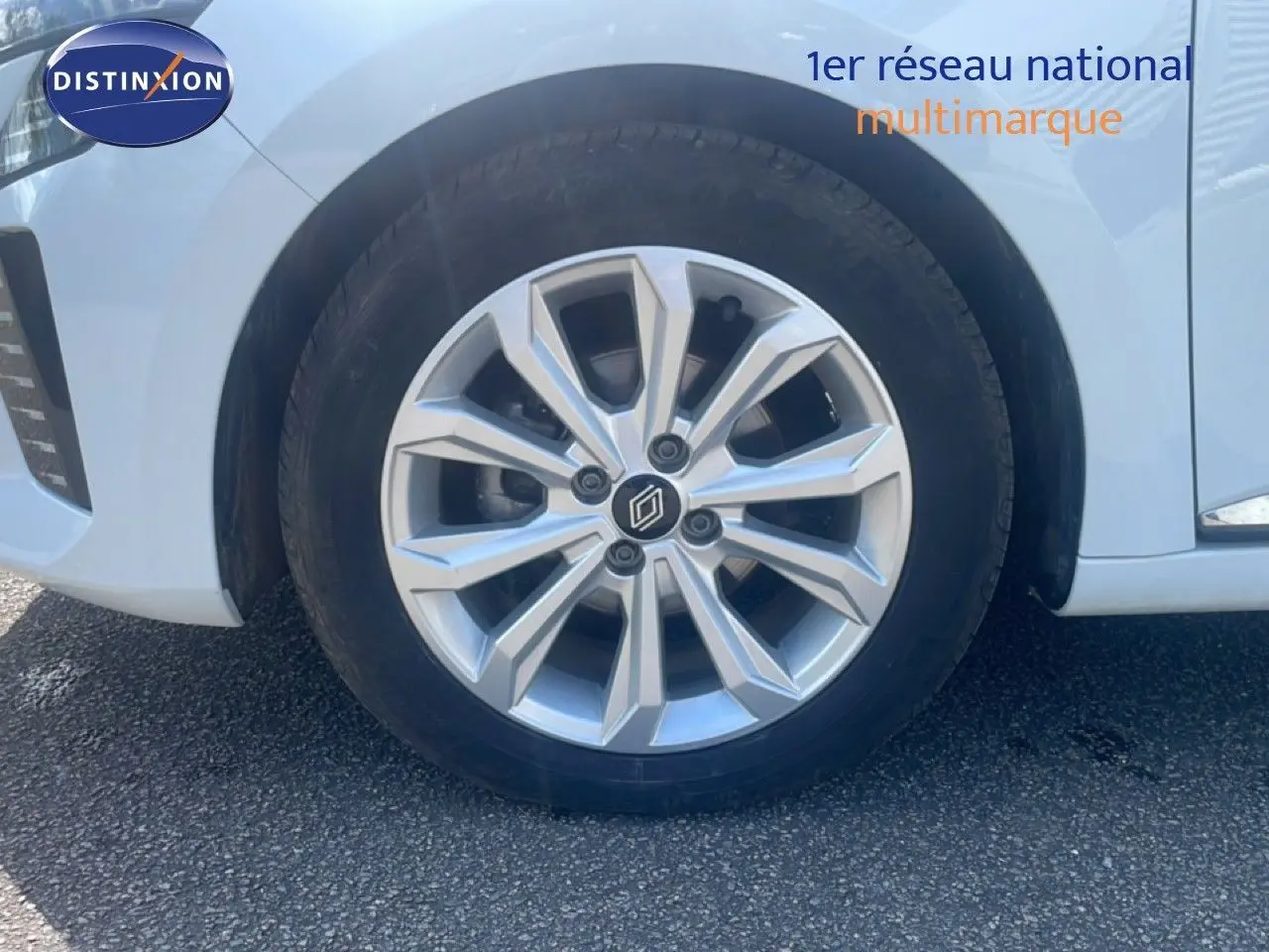 Gros plan sur la roue avant droite d'une Renault Clio blanche 2025 avec jante alliage argentée au design moderne.