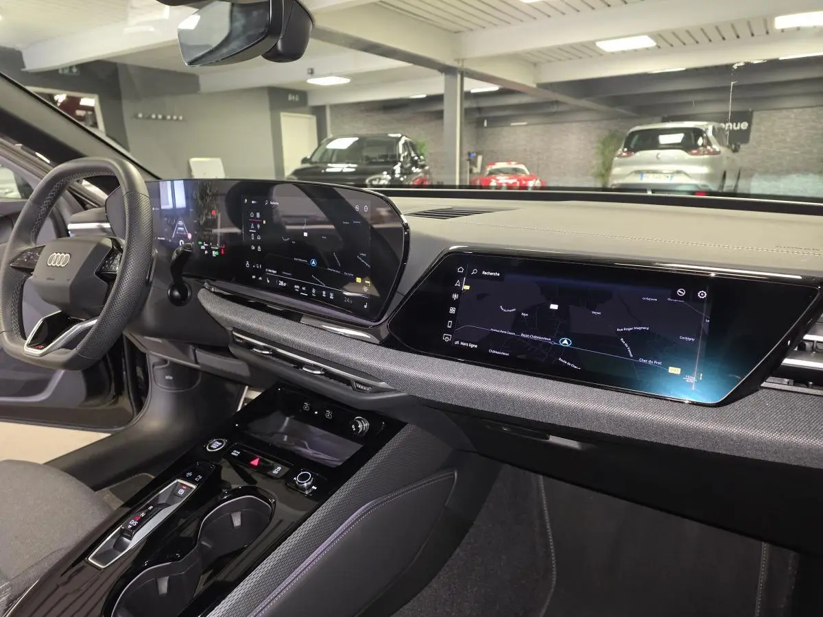 Vue intérieure côté conducteur de l'Audi A5 Avant 2025 noire, avec tableau de bord digital et écran tactile central.