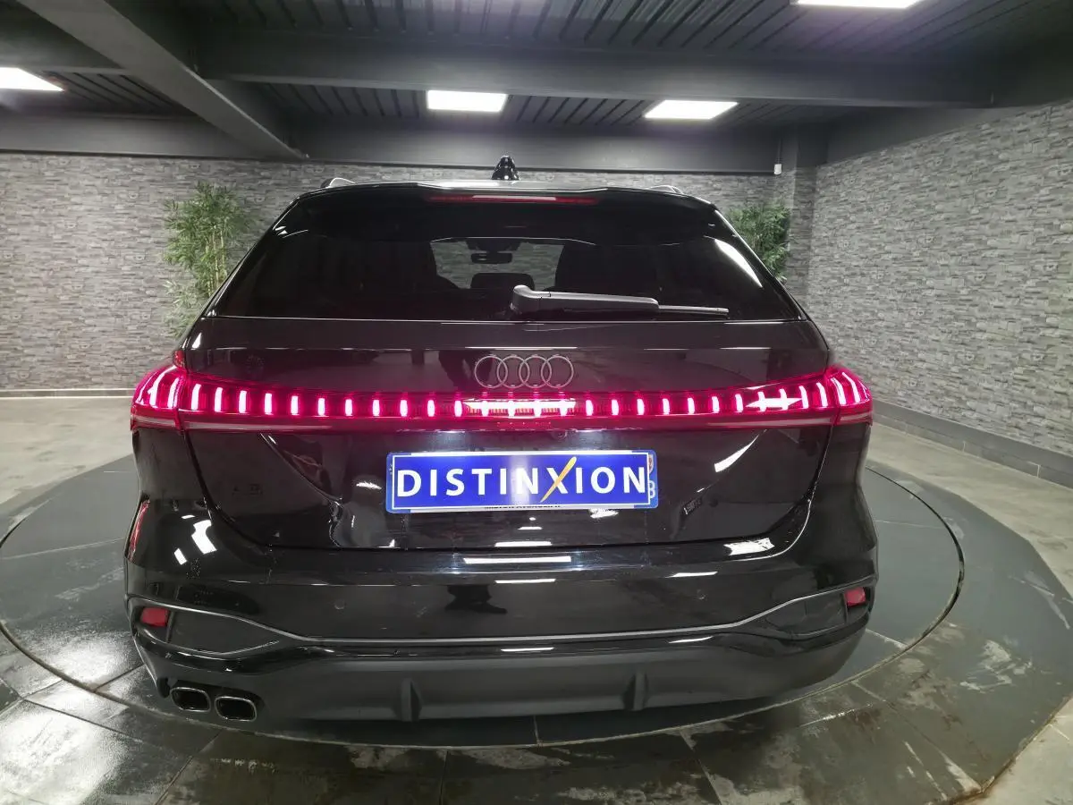 Vue arrière d'une Audi A5 Avant S line noire avec feux arrière LED continus et double sortie d'échappement chromée.