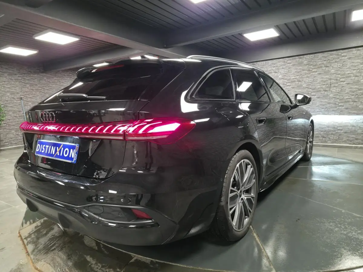 Audi A5 Avant noir vue 3/4 arrière droit, feux arrière LED allumés et jantes 19 pouces style V.