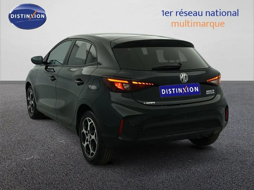 Vue 3/4 arrière droite d'une MG3 1.5 HYBRID+ 195 Luxury noire Pebble Black avec feux arrière allumés et jantes stylées.