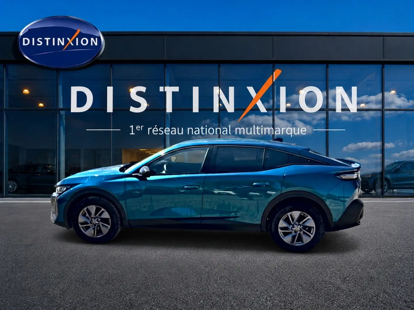 Profil gauche d'une Peugeot 408 Hybrid 145 allure bleu métallisé, avec jantes alu et vitres surteintées, devant une vitrine Distinxion.