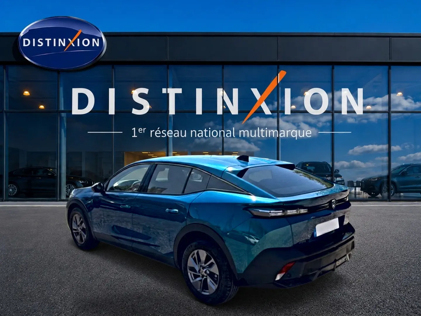 Vue 3/4 arrière droite d'une Peugeot 408 Hybrid 145 allure e-dcs6 bleu métallisé avec jantes alu devant une vitrine Distinxion.