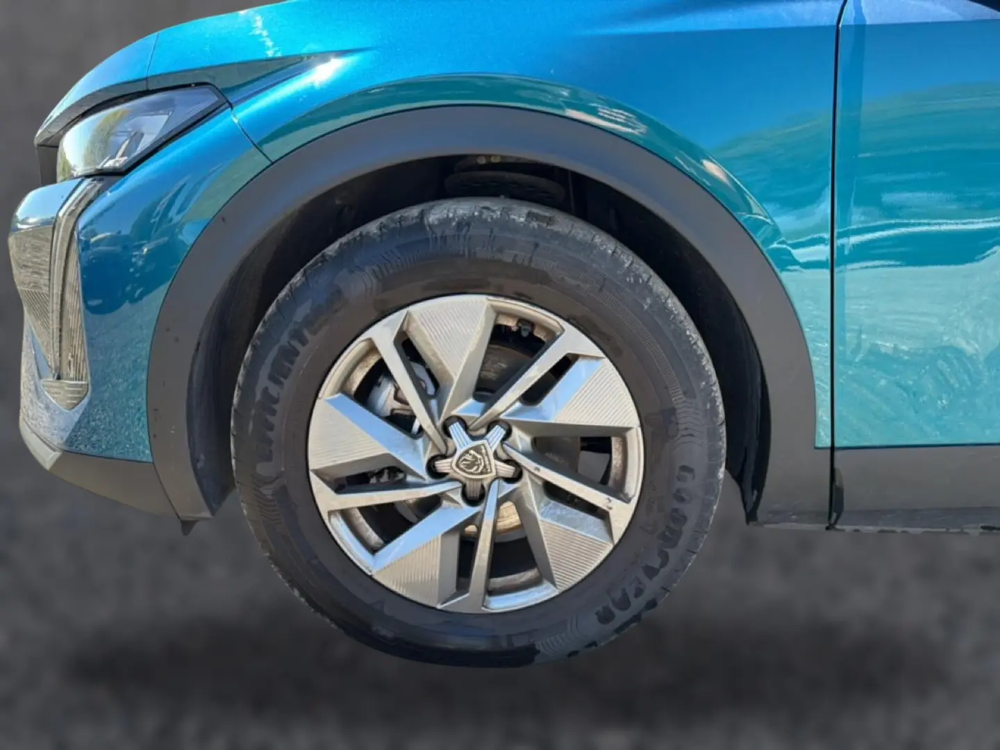Gros plan sur la roue avant gauche d’une Peugeot 408 bleu 2025 avec jante alu au design moderne.