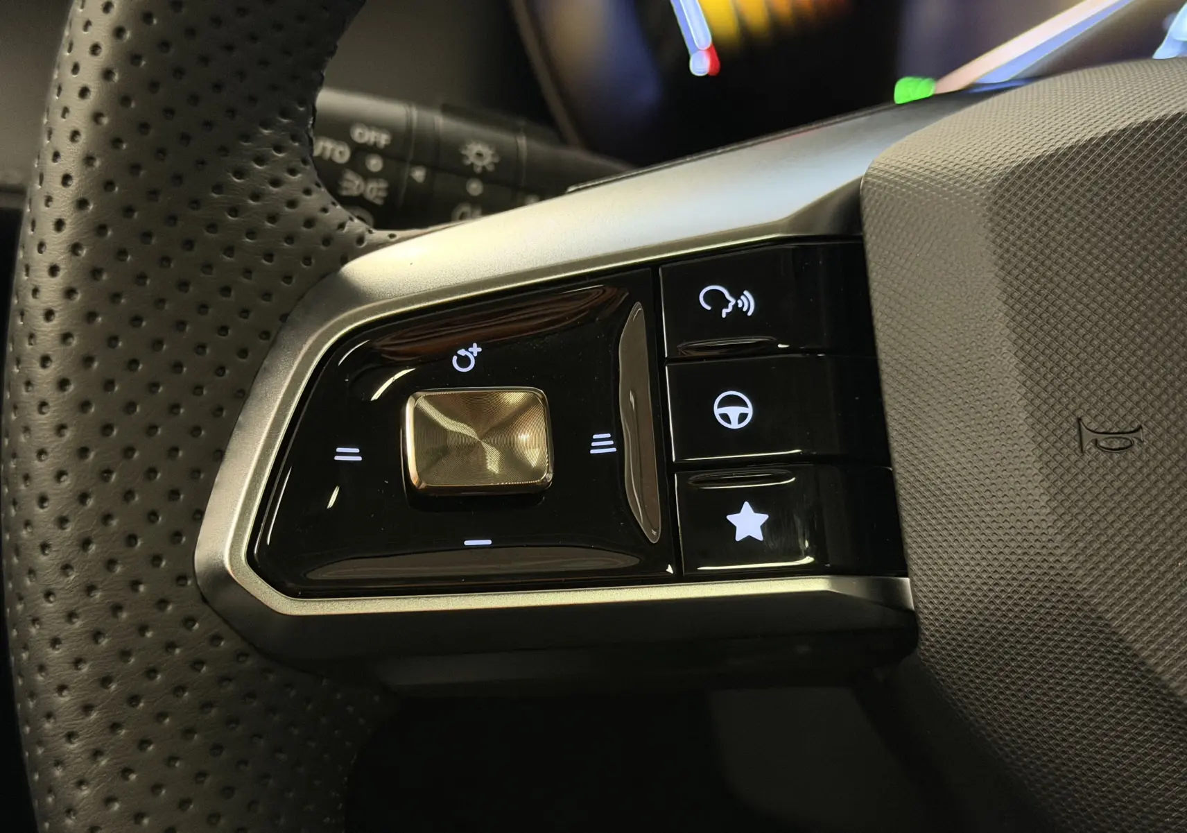 Gros plan sur les commandes noires du volant perforé côté gauche du MG MOTOR ZS 2026 avec boutons rétroéclairés.
