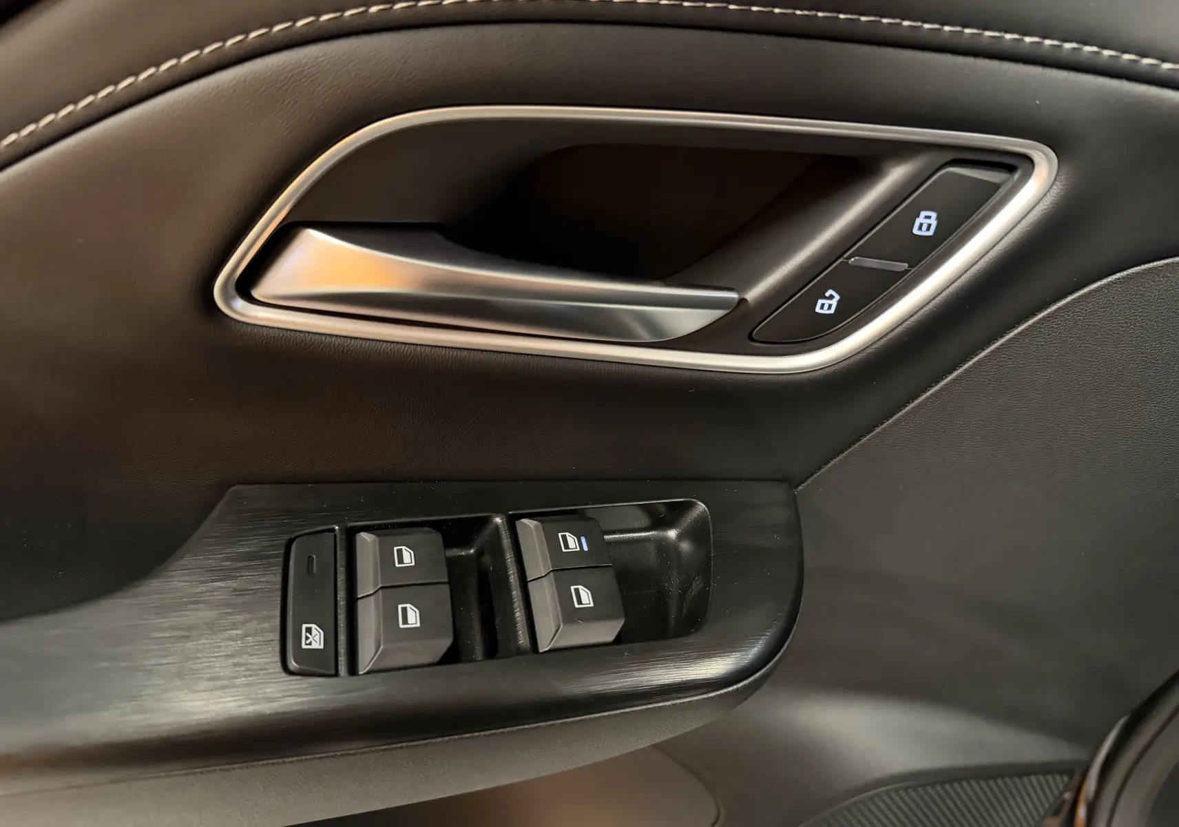 Gros plan sur la poignée intérieure et les commandes de fenêtre côté gauche en finition noire du MG ZS 2026.