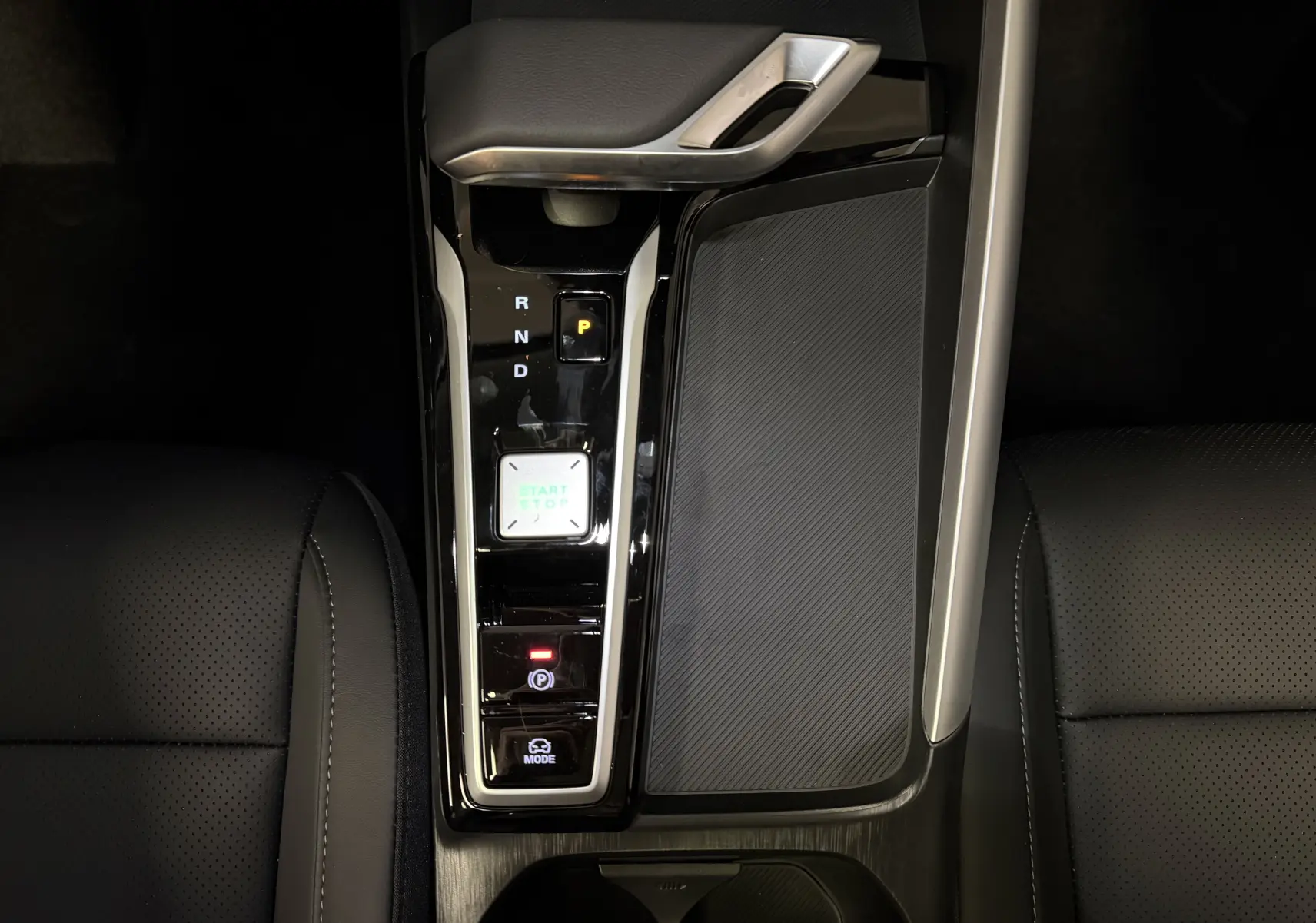 Vue plongeante sur la console centrale noire du MG ZS 2026, avec levier de vitesses automatique et bouton start/stop éclairé.