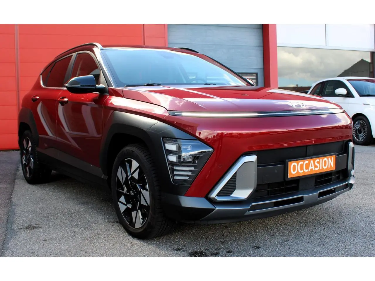 Hyundai Kona 2024 rouge Ultimate Metal avec toit noir, vue 3/4 avant mettant en valeur les feux LED et jantes alliage.