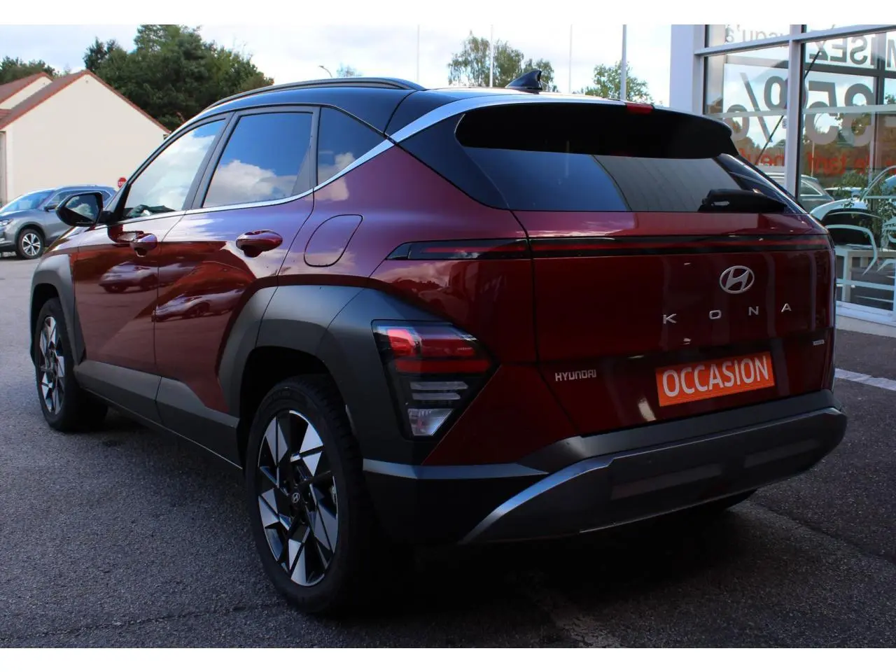 Vue 3/4 arrière droite du Hyundai Kona 2024 rouge Ultimate Metal avec toit noir et jantes alliage 17 pouces.