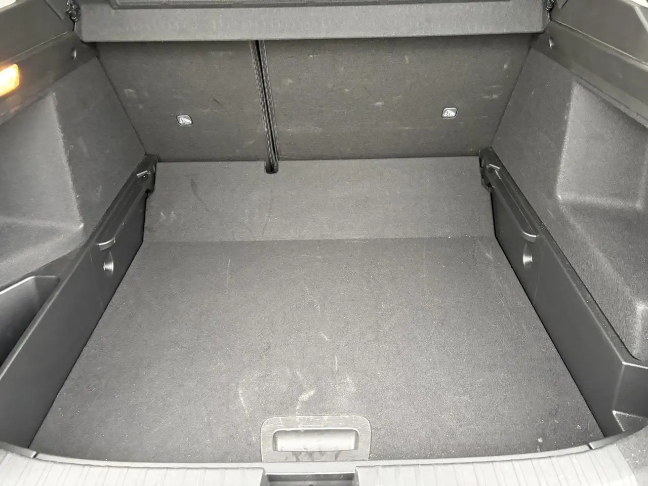 Coffre vide vu de l'intérieur, revêtement noir avec plancher plat et rangements latéraux intégrés.