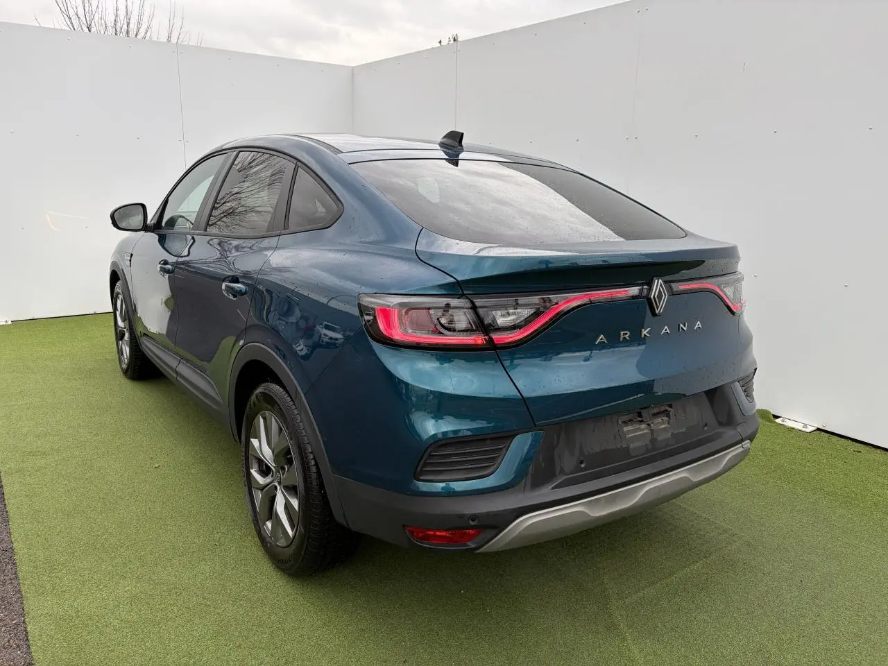 Vue 3/4 arrière droite du Renault Arkana bleu Zanzibar métallisé avec feux arrière LED et jantes alliage grises.