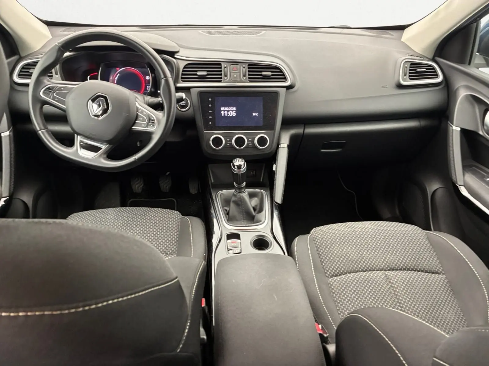 Vue intérieure avant du Renault Kadjar 1.5 Blue dCi 115 Business, tableau de bord noir avec volant multifonction et boîte manuelle.