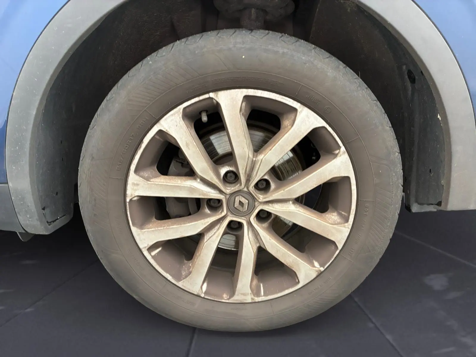 Gros plan sur la roue avant gauche du Renault Kadjar bleu cosmos, mettant en valeur la jante alliage 17 pouces et le logo central.