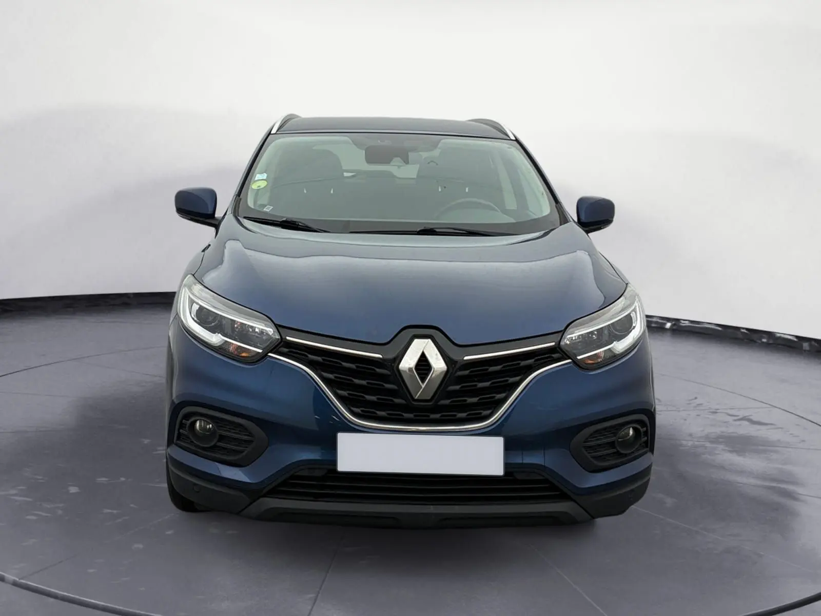 Vue frontale d'un Renault Kadjar 1.5 Blue dCi 115 Business bleu cosmos, avec calandre noire et phares LED allumés.