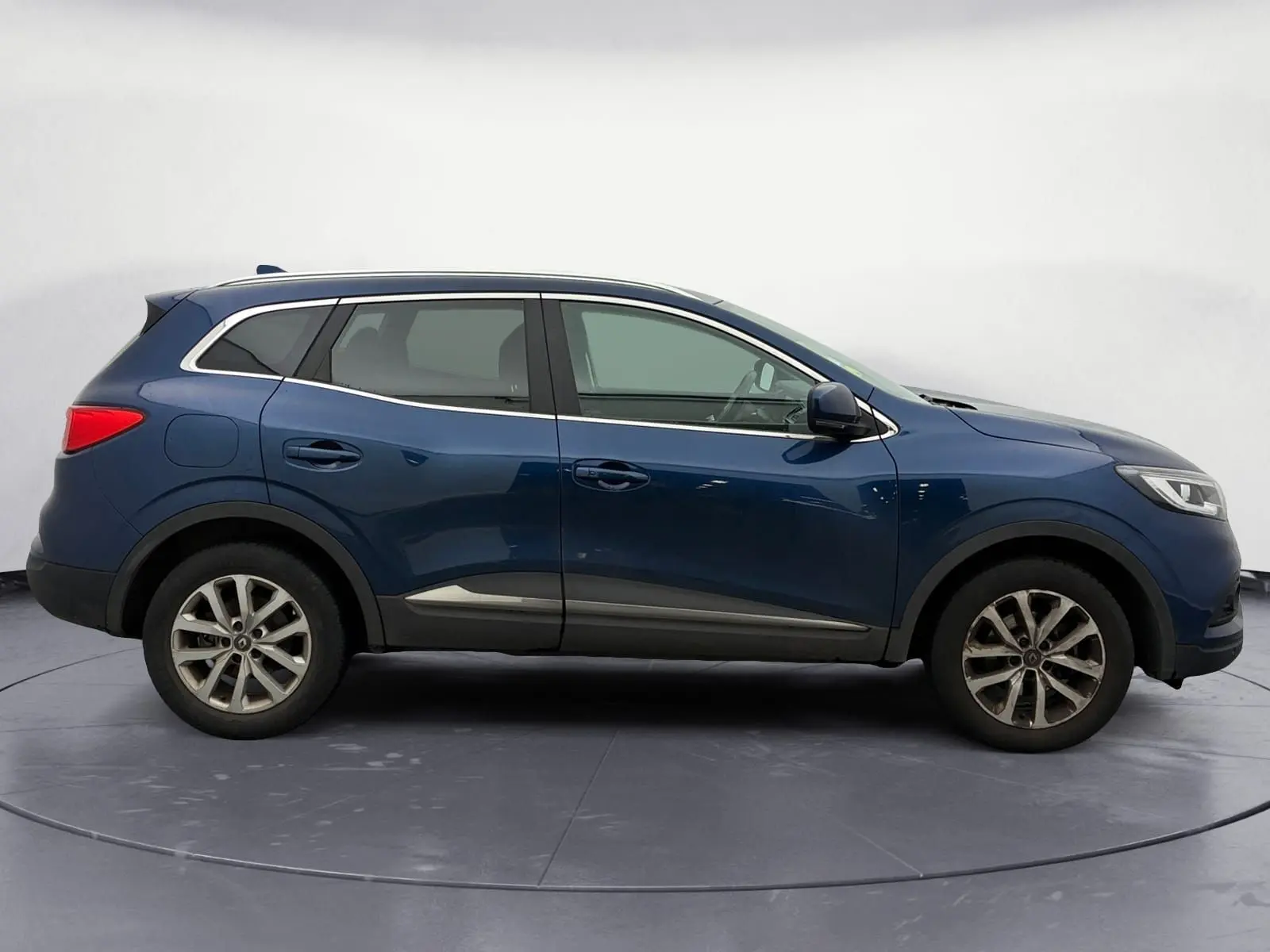 Profil droit d’un Renault Kadjar 1.5 Blue dCi 115 Business bleu cosmos, avec jantes alliage et barres de toit chromées.
