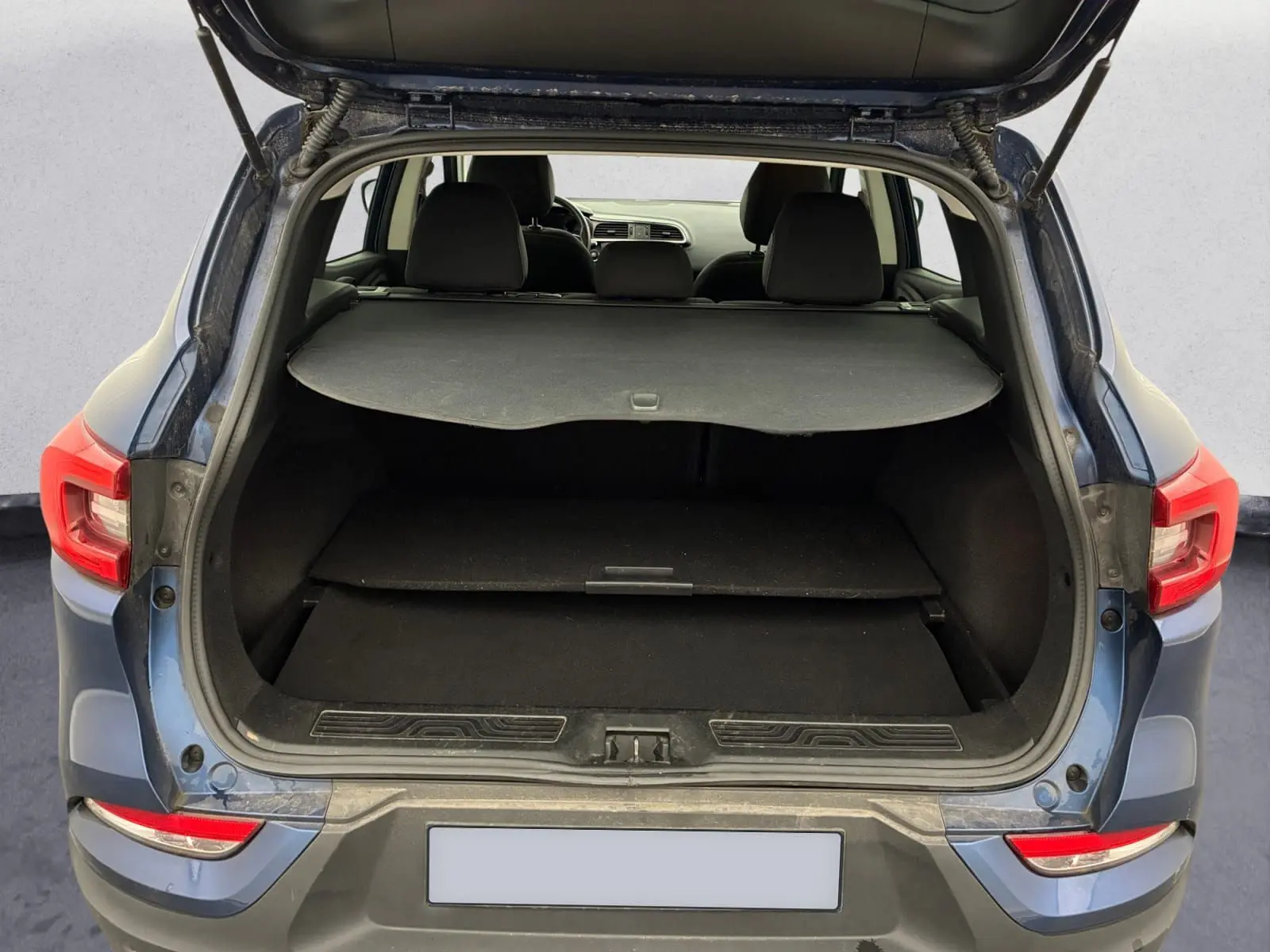 Vue arrière du coffre ouvert du Renault Kadjar bleu cosmos 2020, montrant l'espace de chargement et la tablette cache-bagages.