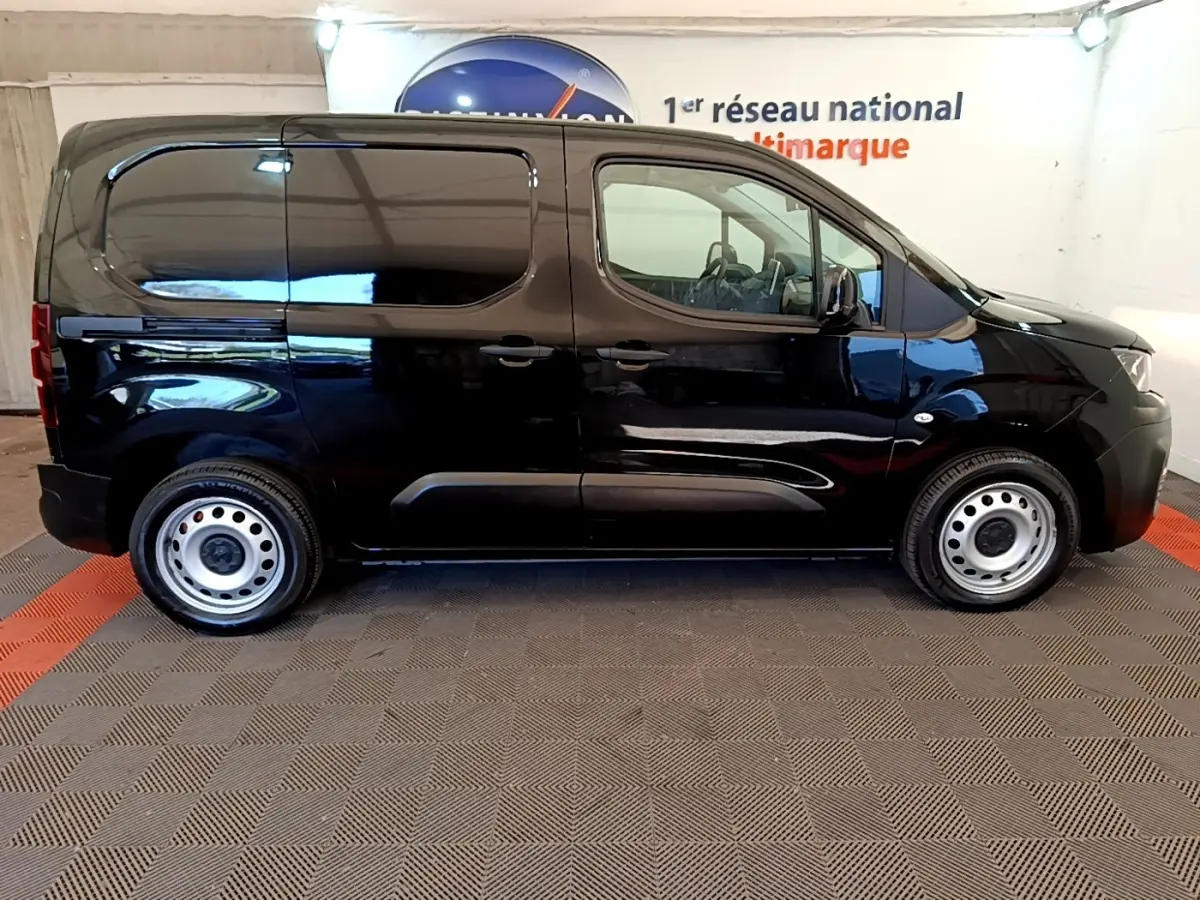 Profil côté droit d’un Peugeot Partner noir 2022 avec jantes acier et cloison pleine visible à l’arrière.