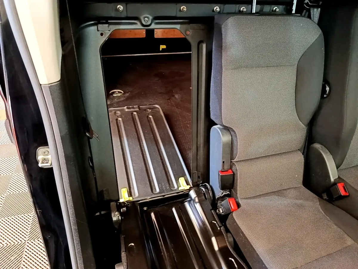 Vue intérieure montrant la cloison pleine et l'ouverture entre l'habitacle et la zone de chargement du Peugeot Partner noir.