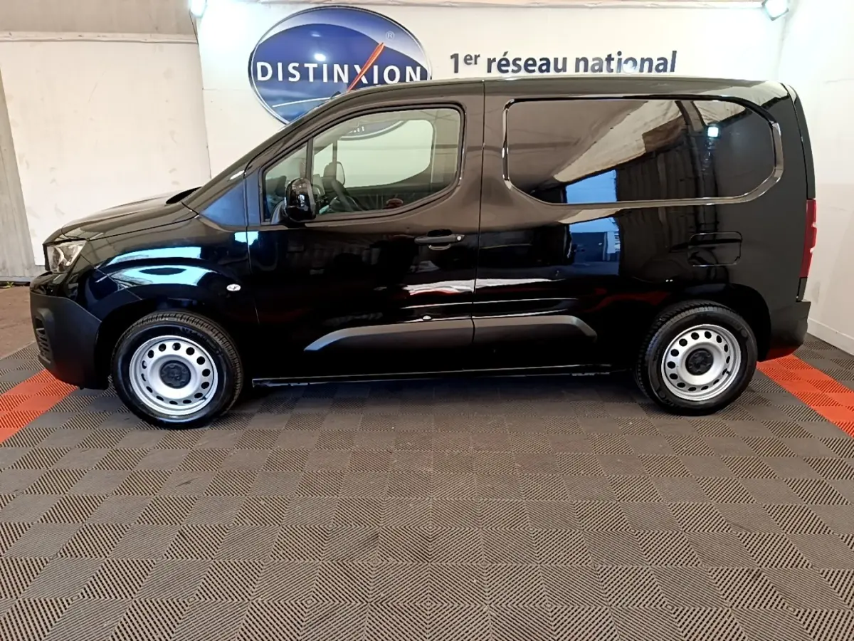 Vue latérale droite d’un Peugeot Partner noir 2022 avec jantes acier et vitres arrière teintées.