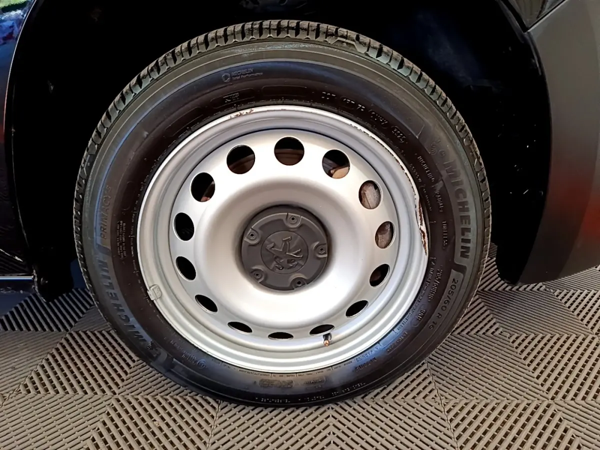 Gros plan sur la roue avant droite en jante acier du Peugeot Partner noir, soulignant le pneu Michelin.