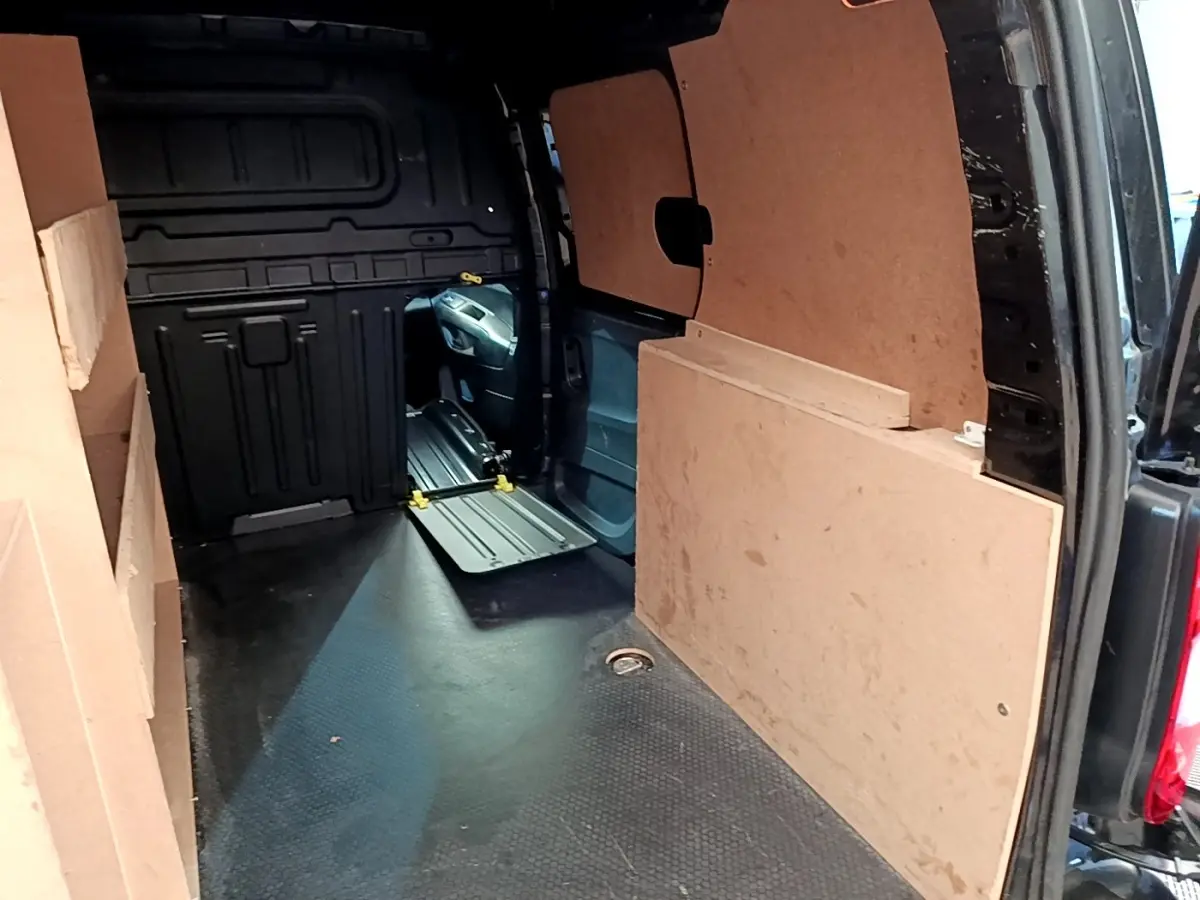 Vue intérieure arrière du Peugeot Partner noir 2022, montrant l'espace de chargement avec cloison pleine en bois.