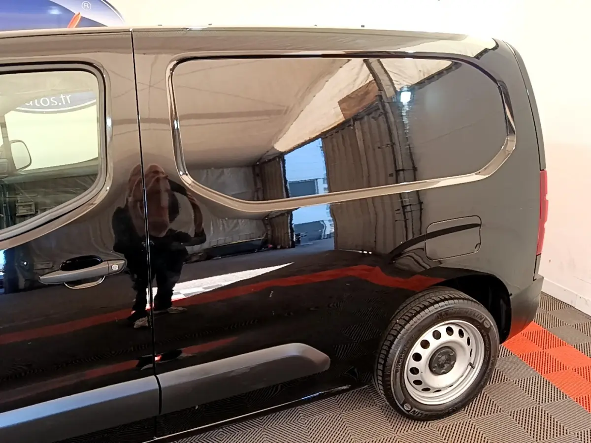 Vue latérale droite du Peugeot Partner noir 2022 avec jante acier et porte latérale coulissante fermée.