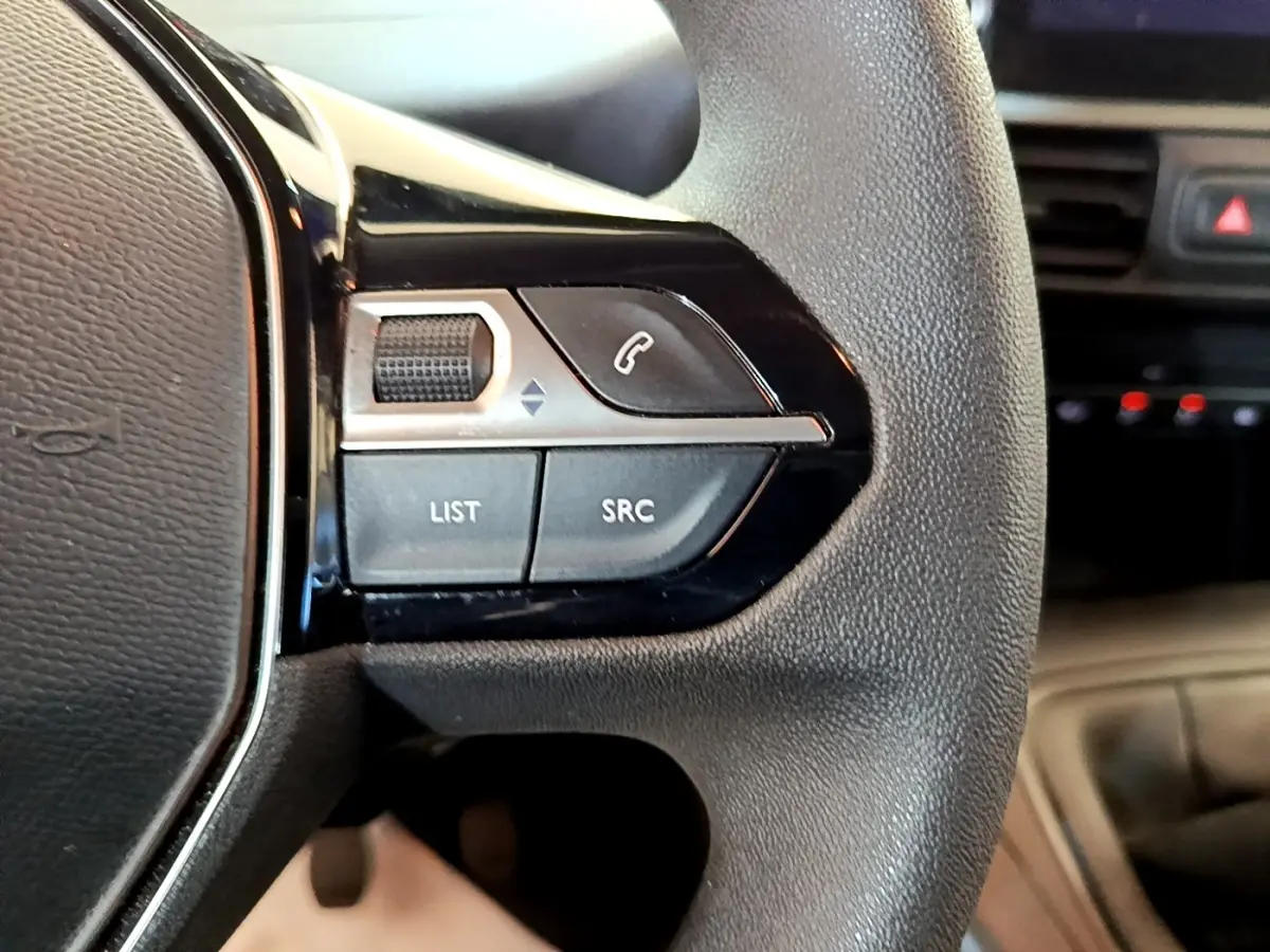 Gros plan sur les commandes gauche du volant noir du Peugeot Partner 2022, avec boutons d’appel et réglages audio.
