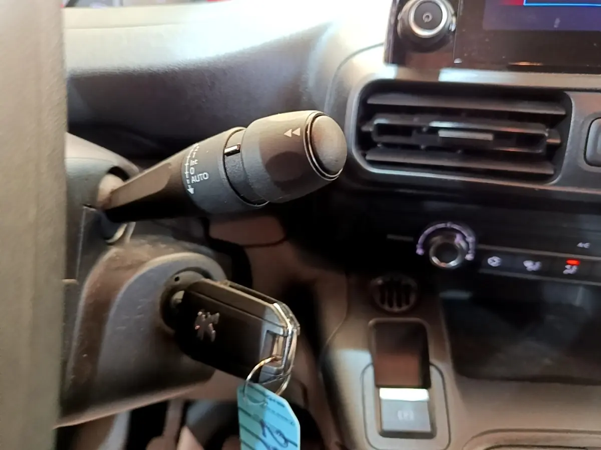 Vue rapprochée de la commande d’essuie-glaces et clé de contact dans l’habitacle du Peugeot Partner noir 2022.