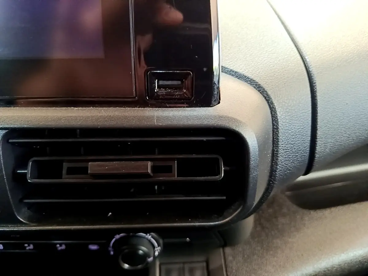 Gros plan sur la console centrale noire du Peugeot Partner 2022, montrant la sortie d’air et un port USB.