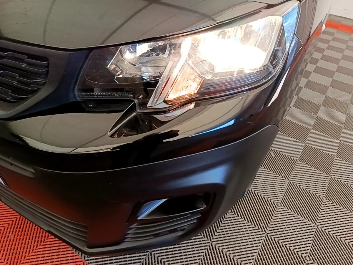 Gros plan sur l'avant droit noir du Peugeot Partner 2022 avec phare allumé et antibrouillard intégré.