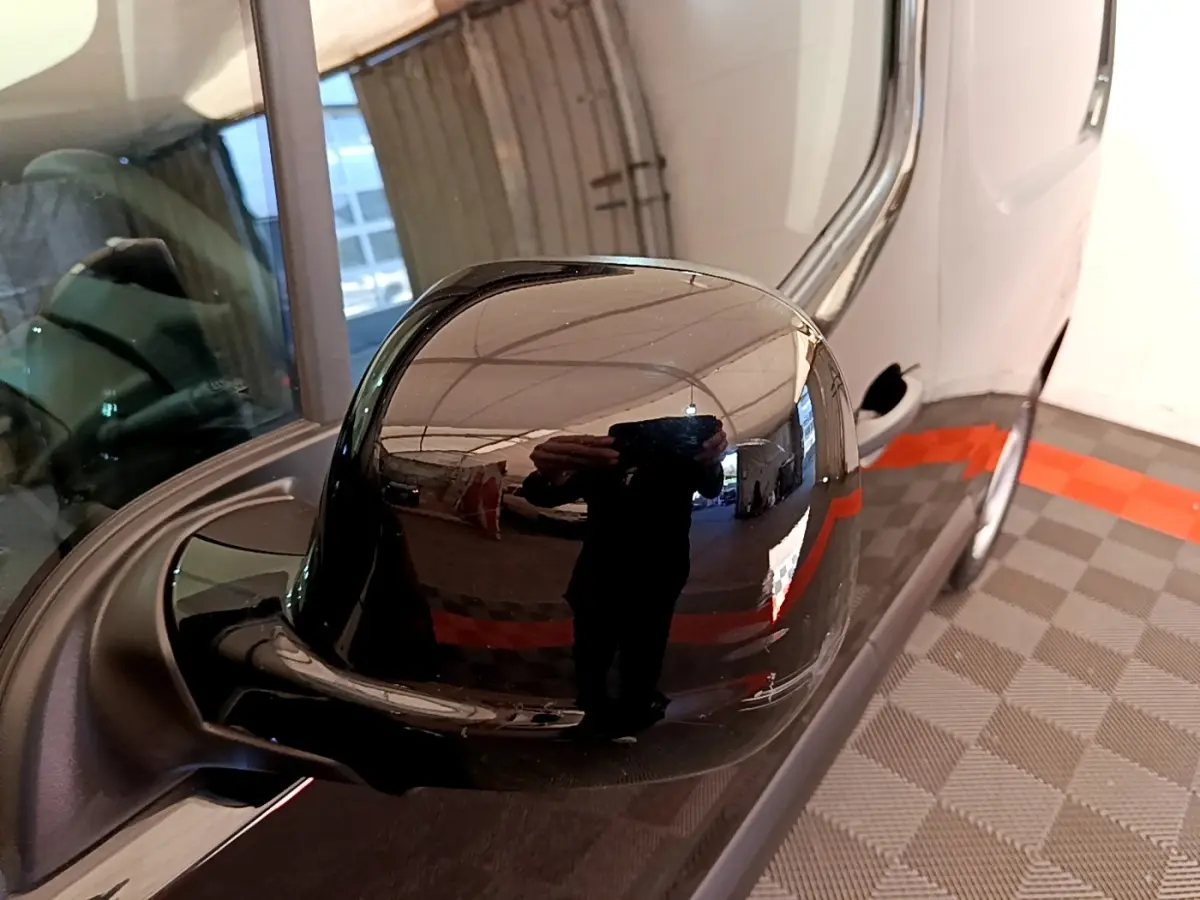 Rétroviseur extérieur noir côté conducteur d'un Peugeot Partner 2022 vu en gros plan avec reflet de l'environnement intérieur.