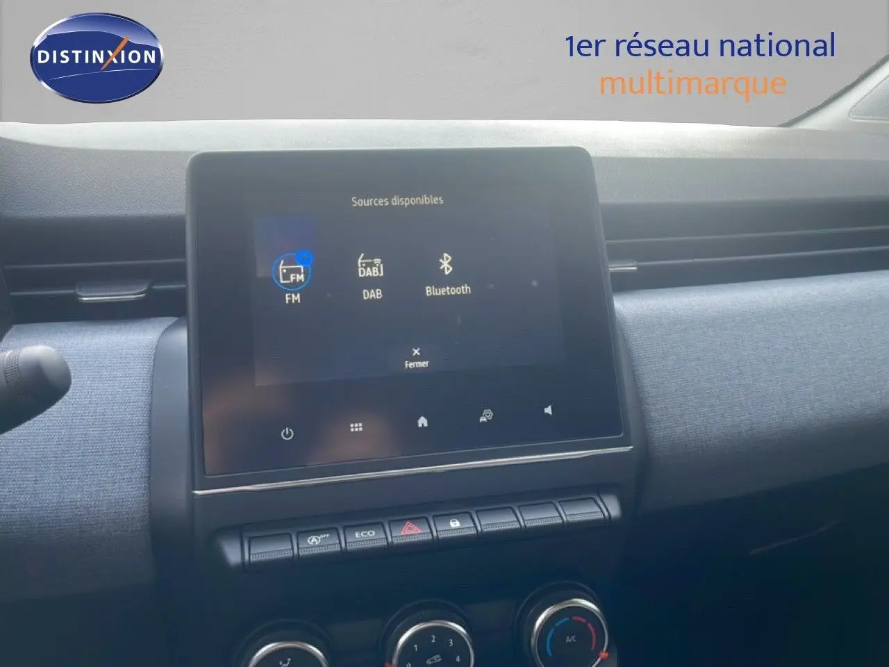 Écran tactile central de la Renault Clio 2025 avec interface multimédia affichant FM, DAB et Bluetooth, tableau de bord gris.