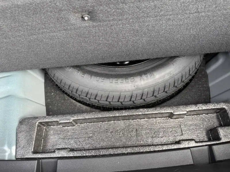 Vue rapprochée de la roue de secours sous le plancher du coffre du Renault Arkana 2025 Bleu Zanzibar.