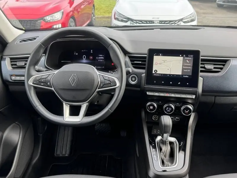 Vue intérieure centrée sur le volant et la console centrale du Renault Arkana 2025 avec écran tactile et commandes modernes.