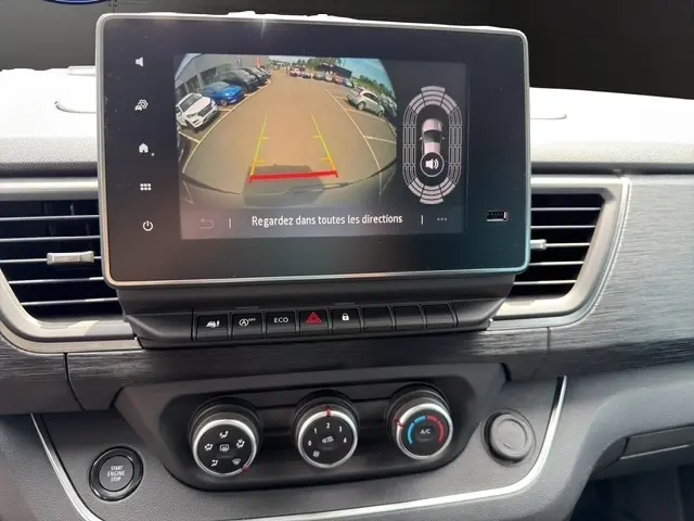 Vue rapprochée de l’écran tactile central du Nissan Primastar 2025 affichant la caméra de recul et les commandes de climatisation.