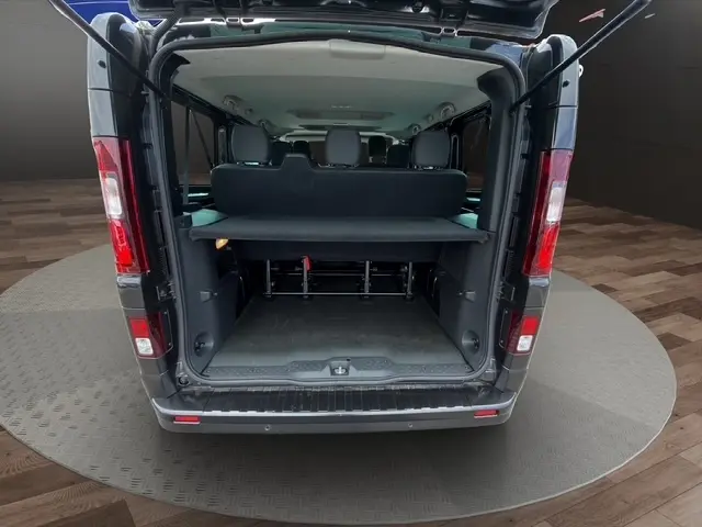 Vue arrière ouverte du Nissan Primastar noir 2025, montrant l'espace de chargement et les sièges arrière rabattus.