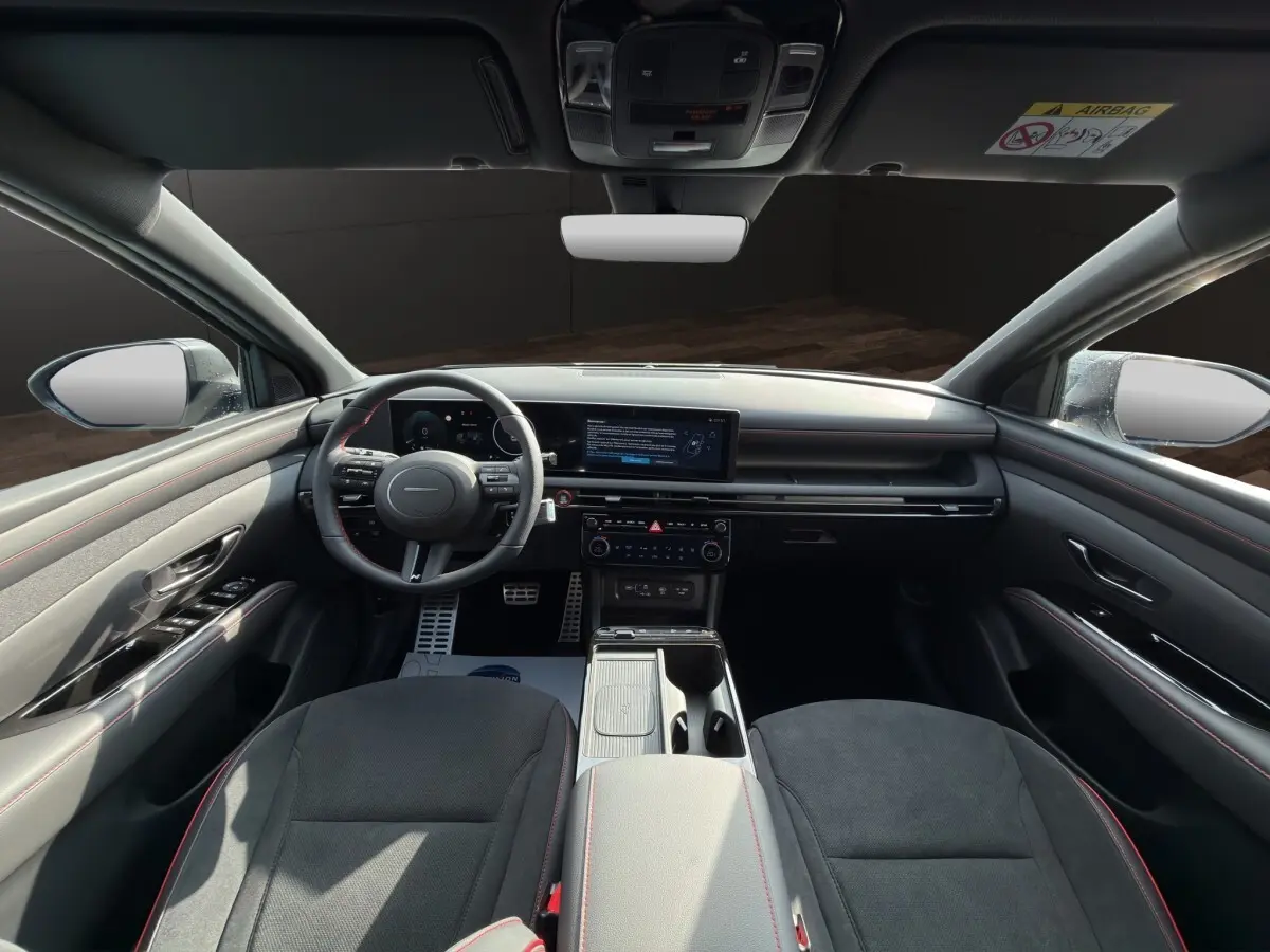 Vue intérieure avant du Hyundai Tucson gris clair 2026, tableau de bord moderne avec écran tactile large et volant multifonctions.