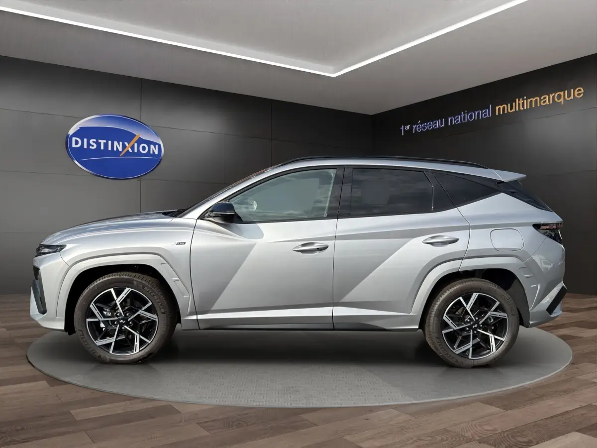 Profil droit du Hyundai Tucson 1.6 Hybrid N Line gris clair avec jantes alliage et lignes anguleuses marquées.
