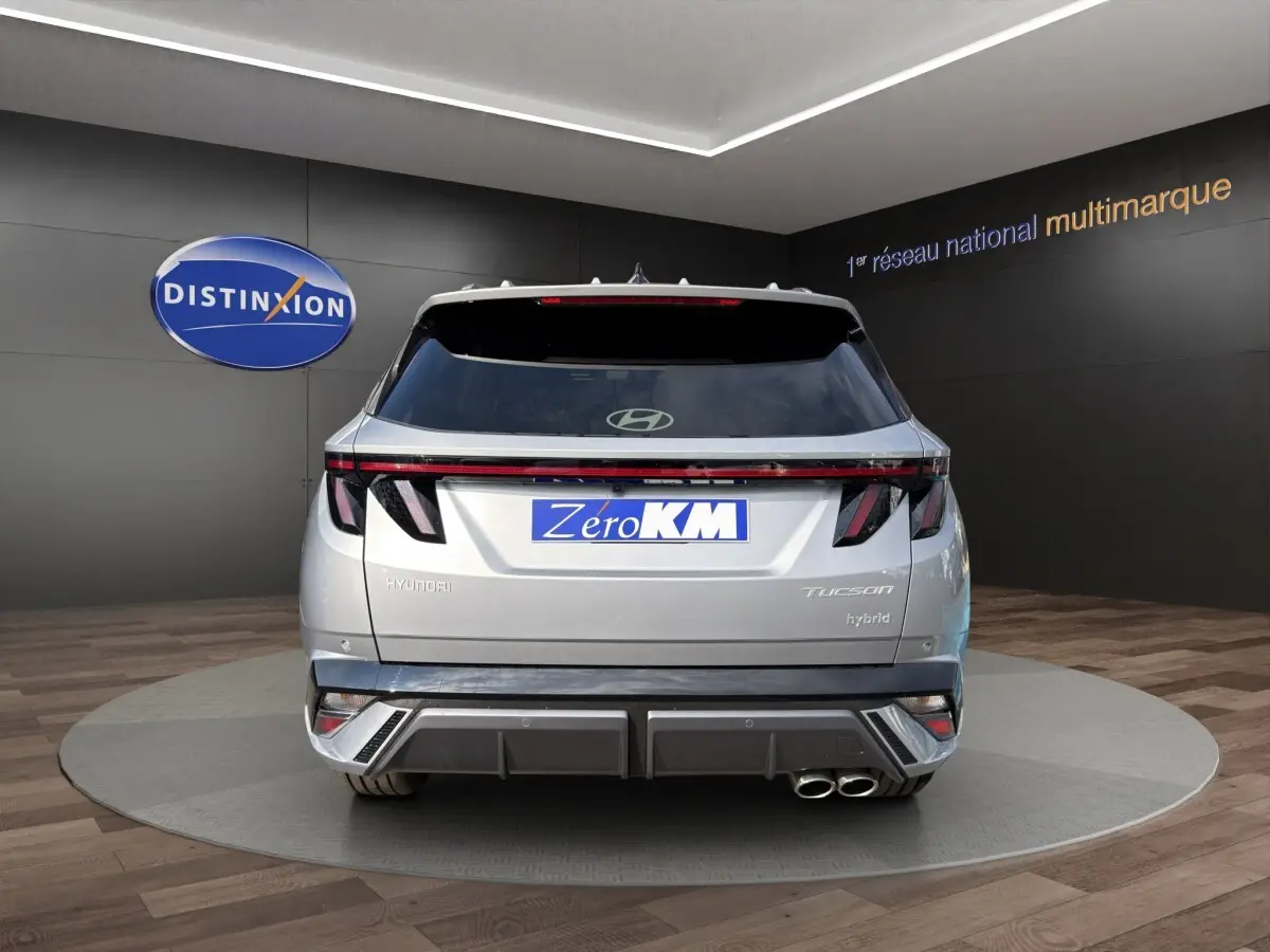 Vue arrière d’un Hyundai Tucson gris clair hybride 2026 avec feux LED et double sortie d’échappement chromée.