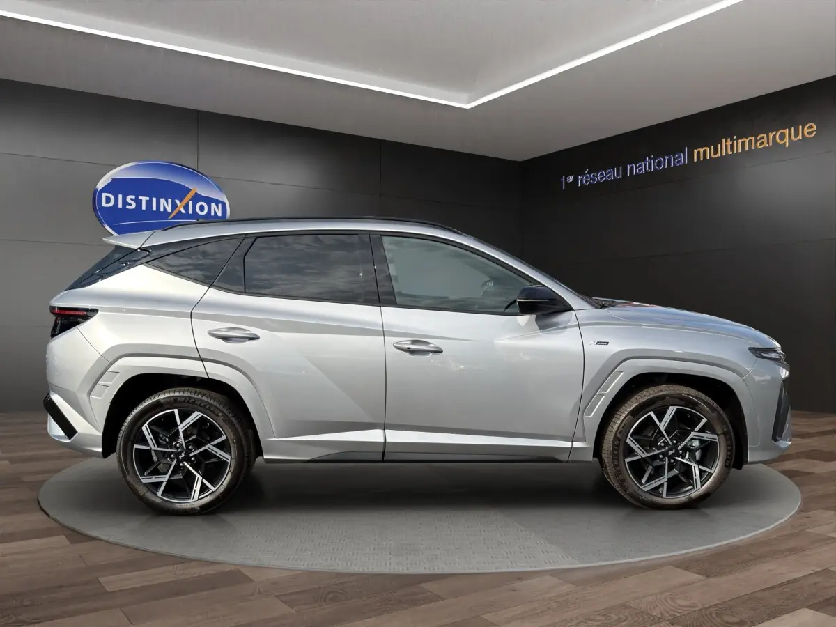 Vue latérale droite du Hyundai Tucson gris clair 2026 avec jantes alliage noires et toit noir contrasté.