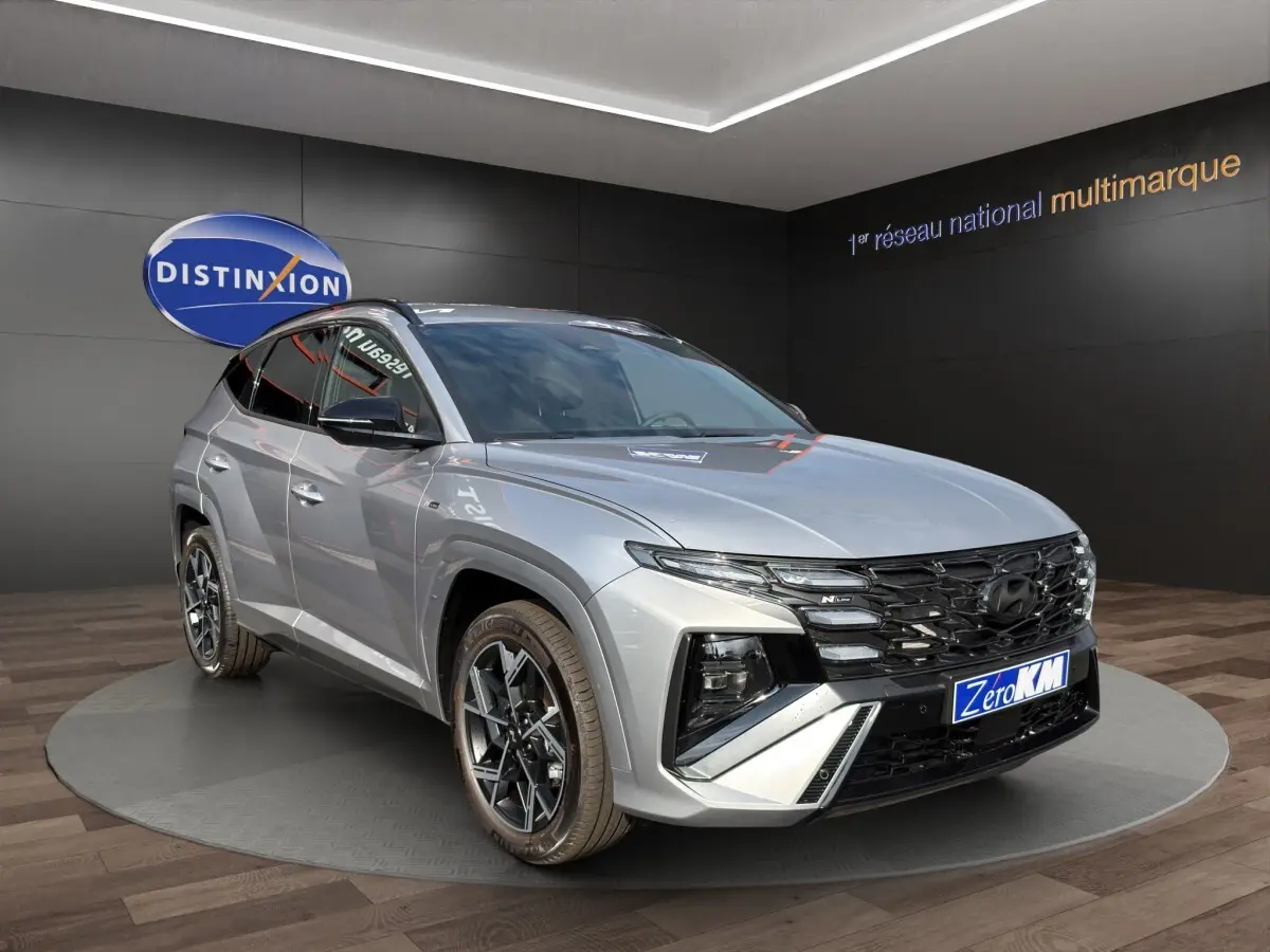 Vue 3/4 avant droit du Hyundai Tucson gris clair 2026 N Line avec calandre noire et jantes alliage distinctives.