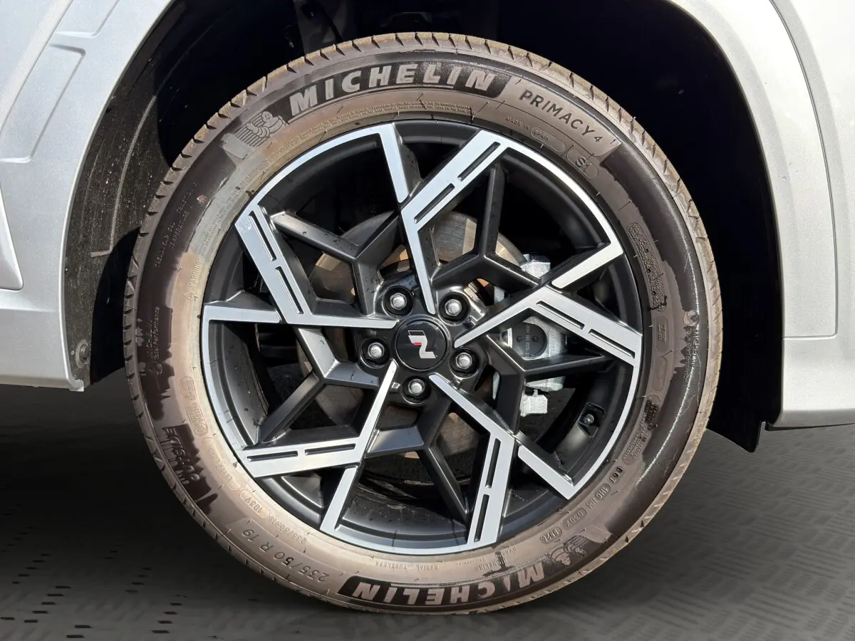 Gros plan sur la roue avant droite gris clair du Hyundai Tucson 1.6 Hybrid N Line avec jante alliage noire et détails argentés.
