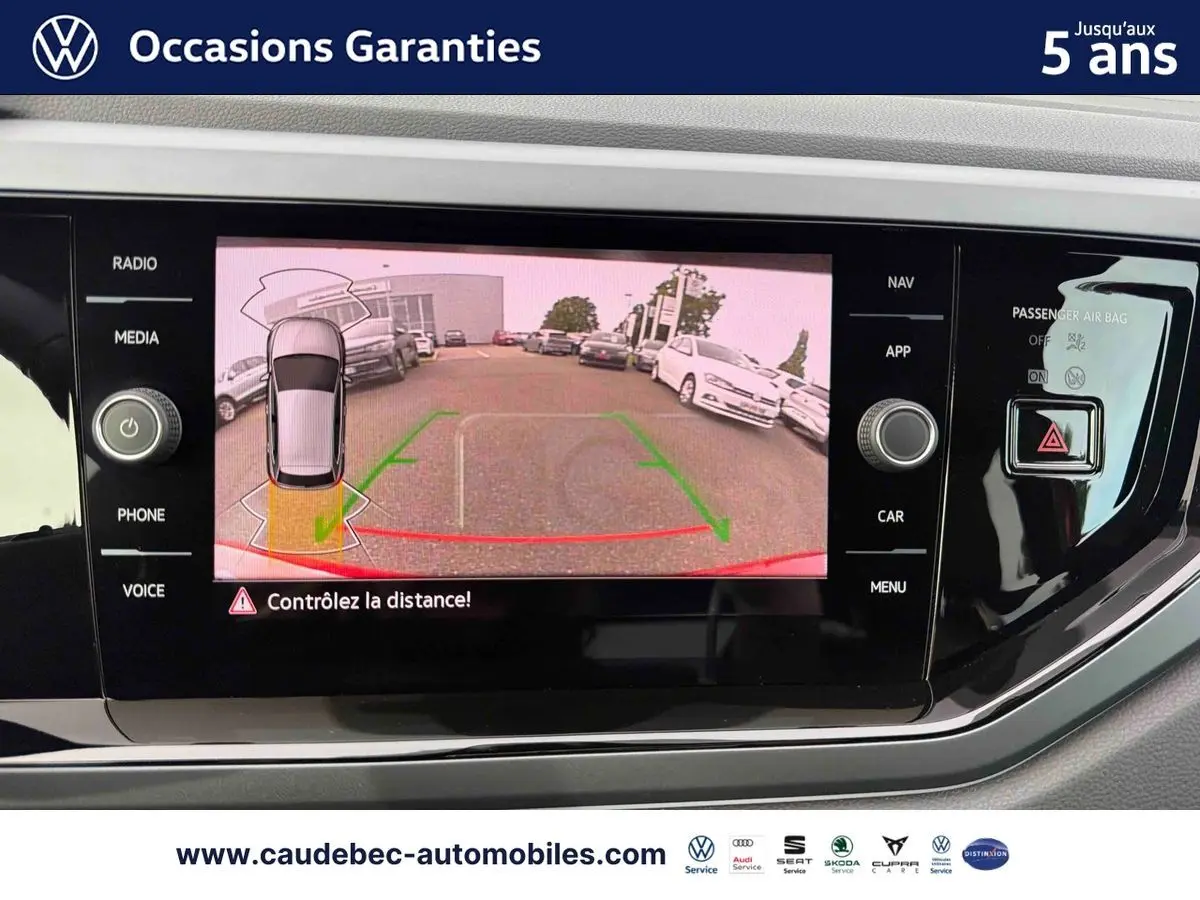 Écran tactile intérieur montrant la caméra de recul d'une Volkswagen Polo rouge vue de l'arrière en stationnement.